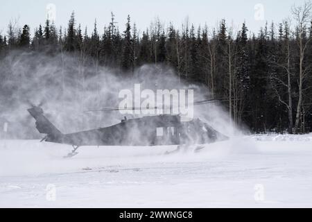 Snow beginnt, als ein Hubschrauber der Alaska Army National Guard UH-60L Black Hawk landet, während er am 28. Februar 2024 das Trainieren von Schleuderlasten auf der Joint Base Elmendorf-Richardson unterstützt. Soldaten der US-Armee des Alaska Army National Guard Aviation Battalion führten das mit Schleudern beladene Training durch, um ihre Einsatzfähigkeit in Alaskas rauer Umgebung zu verbessern. (Alaska Nationalgarde Stockfoto