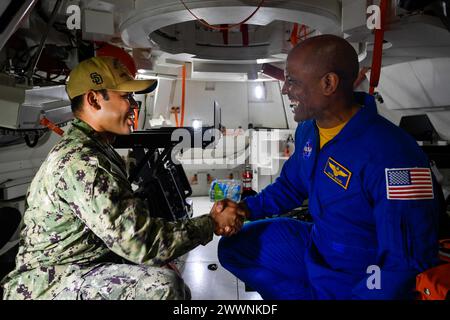 Victor Glover Jr. (rechts) gratuliert dem Machinisten Mate 2nd Class Gerald Castro, einem aus Isabela, Philippinen stammenden Einwohner, nach seiner erneuten Einschreibung in einem Crew-Modul-testartikel (CMTA) an Bord eines Amphibien-Transportdocks der San Antonio-Klasse USS San Diego (LPD 22) während des laufenden Recovery-Tests 11. Februar 2024. In Vorbereitung auf die Mission Artemis II der NASA, die vier Astronauten nach Orion jenseits des Mondes entsenden wird, werden die NASA und das Verteidigungsministerium eine Reihe von Tests durchführen, um die Prozesse, Verfahren und Hardware zu demonstrieren und zu bewerten, die bei der Rec verwendet werden Stockfoto