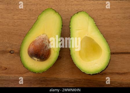 Nahaufnahme einer Avocado, die in Hälften geschnitten wurde, auf einem hölzernen Snackbrett liegend. Stockfoto