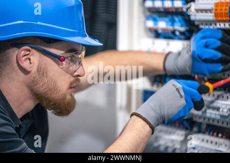 Ein Elektriker arbeitet in einer Schalttafel mit einem elektrischen Anschlusskabel. Stockfoto