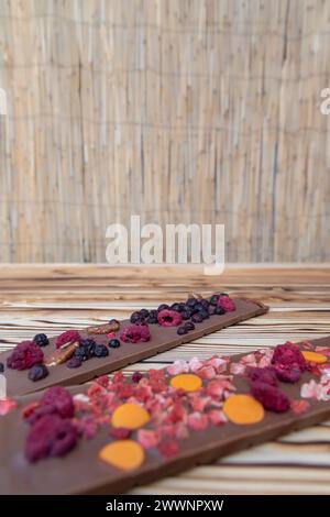 Verschiedene Arten von Schokolade mit getrockneten Früchten auf einem Holzbrett Stockfoto