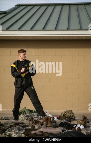 Der erste Tag des 310. ESC Best Warrior Competition, der am 4. Februar 2024 im Camp Atterbury, Indiana, stattfand, begann mit den ersten drei Wettkämpfen des Konkurrenten: Größe und Gewicht, Anordnung der Ausrüstung und einem schriftlichen Test. Sgt. Zachary Lucas zeigt dem Grader seine Handschuhe während der Gangplanung. Stockfoto