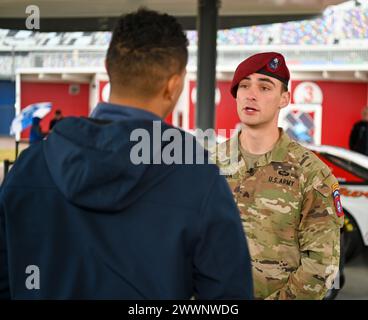 Sergeant Nolan Svoboda, ein Fallschirmjäger, der dem 82. Luftlandedivision 2. Bataillon, 505. Infanterieregiment der US Army zugeteilt wurde, nimmt an einem Fernsehinterview während der NASCAR Daytona 500 2024 in Daytona Beach, Florida, am Sonntag, 18. Februar 2024 Teil. Das Daytona 500 ist ein 500 km langes Motorrennen der NASCAR Cup Series, das jährlich ausgetragen wird und als das wichtigste und prestigeträchtigste Rennen im NASCAR-Kalender gilt. Stockfoto