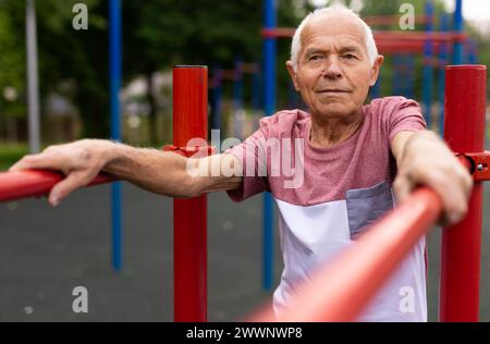 Alter Mann, der im Freien zwischen parallelen Gittern steht Stockfoto