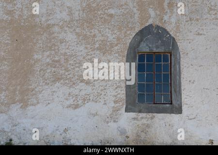 Fenster im gotischen Stil rechts von einem alten ungenutzten Kirchengebäude eingerahmt. Auf der linken Seite ist die Farbe abblättert und der Kopierraum ist ebenfalls vorhanden. Stockfoto