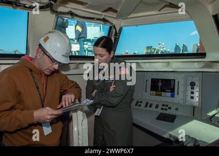 Newport News, V.A. (14. Februar 2024) – Lt. Cmdr. Katie Greiner diskutiert eine Checkliste mit einem HII-Auftragnehmer im Integrated Catapult Control System (ICCS) während der ersten „Totlast“-Prüfung des elektromagnetischen Flugzeugstartsystems (EMALS). In dieser Testphase werden große, fahrzeugartige Strukturen mit einem Graduiertengewicht von bis zu 80.000 Pfund vom Bug des Flugzeugs in den James River geworfen, um das Gewicht des Flugzeugs zu simulieren. John F. Kennedy ist der zweite Flugzeugträger der Ford-Klasse und befindet sich im Bau der Newport News Shipbuilding (NNS) Division in Newport News. Stockfoto