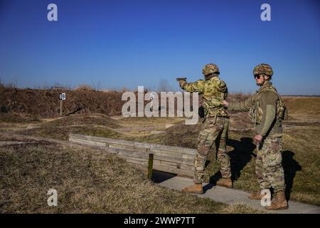 Der zweite Tag des 310. ESC Best Warrior Wettbewerbs begann am 5. Februar 2024 mit der Qualifikation der Soldaten mit M17-Pistole in Camp Atterbury, Indiana. Ein Kadermitglied stabilisiert den Teilnehmer während des Gehabschnitts der Qualifikationsbahn. Stockfoto