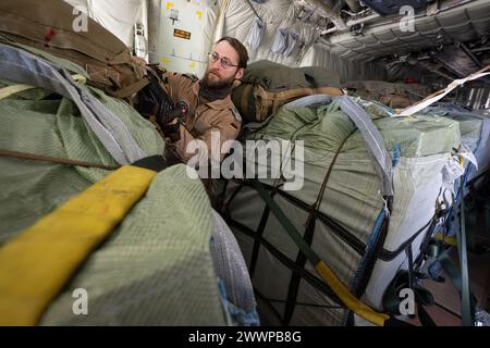 Amman, Jordanien. März 2024. Ein Laderaummeister prüft die Befestigung der Zurrgurte auf Paletten von Hilfsgütern an Bord eines C-130 Hercules Transportflugzeugs der Deutschen Luftwaffe. Die Bundeswehr beteiligt sich mit anderen Nationen an Hilfsflügen, bei denen die Hilfsgüter aus Transportflugzeugen fallen gelassen werden. Quelle: Boris Roessler/dpa/Alamy Live News Stockfoto