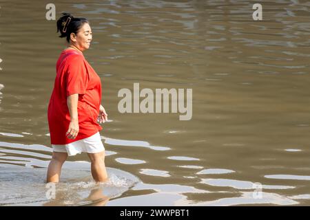 SAMUT PRAKAN, THAILAND, Februar 2024, Eine Frau waten durch eine überflutete Straße Stockfoto