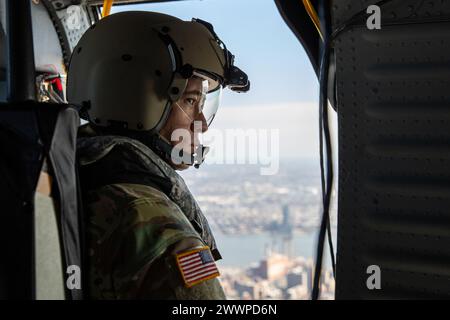 Christian Santodomingo, der dem 3. Sturmhubschrauberbataillon, 142. Aviation Regiment, zugeteilt wurde, schaut am 9. Februar 2024 um seinen UH-60M Black Hawk Hubschrauber am Himmel über Manhattan, New York. Die New York Air and Army National Guardsmen veranstalteten einen Überflug von New York City während eines Besuchs schwedischer Verteidigungsdelegierter. Armee-Nationalgarde Stockfoto