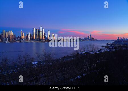 WEEHAWKEN, NJ -18. Februar 2024 - Blick bei Sonnenuntergang auf die Skyline des Ufers in Manhattan, New York, von der anderen Seite des Hudson River in New Jersey. Stockfoto
