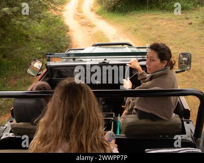 Ein Safari-Fahrer/Reiseleiter vor dem Fahrersitz des landrover Defender, der mit Passagieren über die Tierwelt im Amakhala Game Reserve spricht Stockfoto