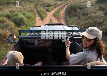 Ein Safari-Reiseleiter fährt einen offenen landrover Defender Jeep im Busch, um Ökotouristen im Luxusurlaub Fakten über die Safaritiere zu erklären Stockfoto