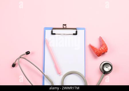 Endokrinologie. Stethoskop, Clipboard, Modell der Schilddrüse und Stift auf rosa Hintergrund, flache Lage Stockfoto