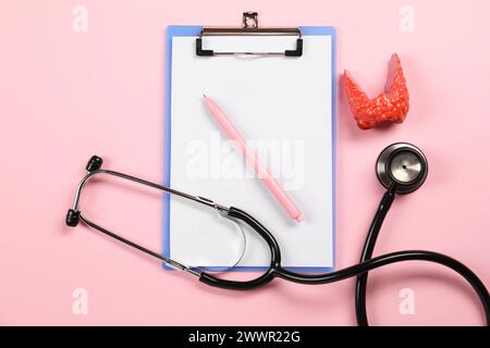 Endokrinologie. Stethoskop, Clipboard, Modell der Schilddrüse und Stift auf rosa Hintergrund, flache Lage Stockfoto