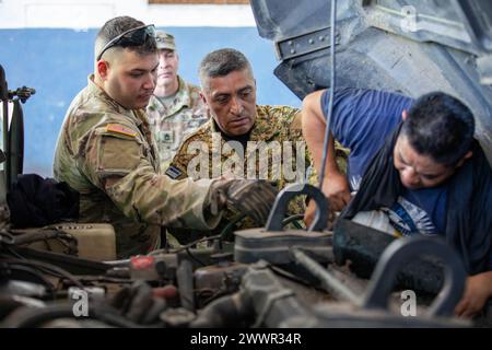 (Von links) PFC. Rodney Quezada, ein Missionsübersetzer und ein Radfahrzeugmechaniker bei der 237. Militärpolizeikompanie, 54. Truppenkommando der New Hampshire Army National Guard, unterstützt Sgt. Refrain Guzman, ein Motorpool-Sgt. Mit Kavallerie-Regiment, Fuerza Armada de El Salvador, während des Ablassens von Getriebeöl während eines Bereitschaftstrainings im Rahmen des New Hampshire National Guard-El Salvador State Partnership Program auf der Basis des Kavallerie-Regiments in Sitio del Nino, El Salvador am 16. Februar 2024. „Wir sind sehr stolz darauf, dass sie hier sind und Wissen teilen können“, sagte Guzman. "Sie ließen uns an mir arbeiten Stockfoto