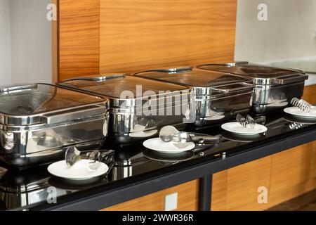 Reihe geschlossener Buffetgerichte im Partybanketsaal. Wartungsbereite Scheuerschale aus Edelstahl am Buffet. Stockfoto