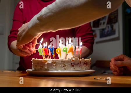 Hände mit Streichhölzern zünden vax Kerzen auf Geburtstagskuchen an Stockfoto