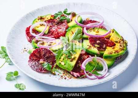 Blutorangen-Salat mit Avocado, Pistazien und roten Zwiebeln, weißer Hintergrund, Nahaufnahme. Stockfoto