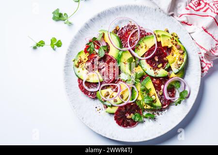 Blutorangen-Salat mit Avocado, Pistazien und roten Zwiebeln, Blick von oben, weißer Hintergrund. Stockfoto