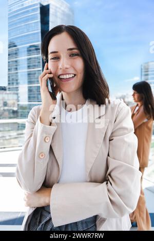 Eine Frau redet auf ihrem Handy. Sie lächelt und ist gut gelaunt Stockfoto