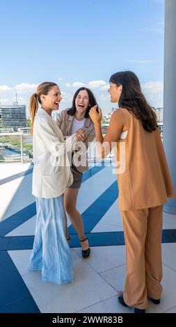 Drei strahlende Frauen teilen einen Moment der Freude, ihr Lachen und Lächeln erhellt die Szene. Stockfoto