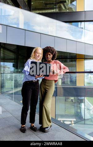 Zwei Frauen mit ähnlichen Merkmalen stehen nebeneinander, lächelnd, vor der großen Architektur. Stockfoto