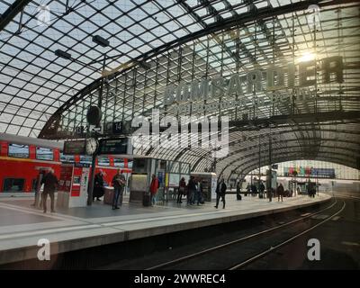 Ein belebter Bahnhof mit Passagieren, die in der Morgensonne warten Stockfoto