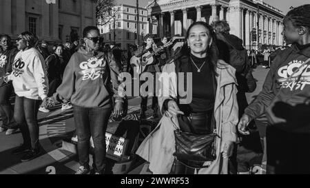 Ein Schwarzweiß-Bild eines Straßenhändlers, der geduldig wartet, während die Streams of Joy-Gruppe ein spontanes christliches Sing-A-Long-Meeting in London durchführen. Stockfoto