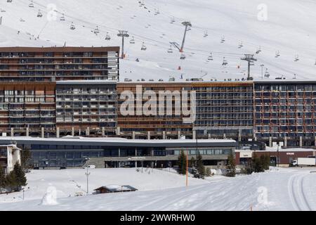 Das Sportzentrum Tignespace liegt niedrig vor einer mehrstöckigen Unterkunft mit Blick auf den See im französischen Skigebiet Tignes. Stockfoto