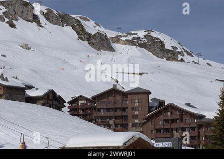 Skifahrer, die die Rote Piste „Bleuets“ in Tignes, Frankreich, über den Chalets des Almes-Viertels in diesem eigens erbauten, hochgelegenen Skigebiet hinunterfahren. Stockfoto