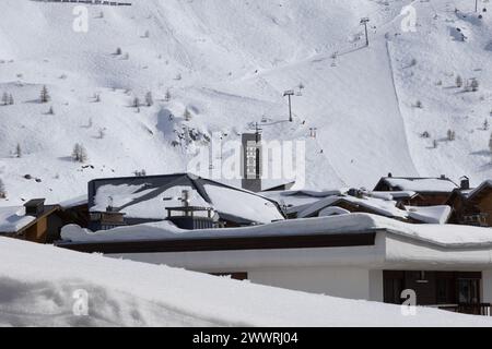 Der Glockenturm der modernistischen römisch-katholischen Kirche erhebt sich über schneebedeckten Dächern von Tignes, einem speziell erbauten Skigebiet in den französischen Alpen. Stockfoto