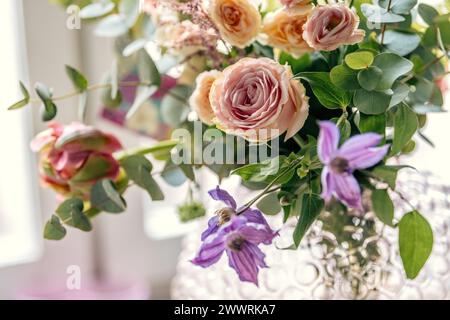 Eine Vielzahl von Blumen in einer Vase an einem Fenster auf einem Tisch Stockfoto