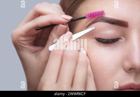 Master makeup korrigiert und gibt Form mit Pinzette zuvor mit Henna Augenbrauen in einem Schönheitssalon gemalt zu ziehen. Professionelle Pflege für Gesicht. Stockfoto