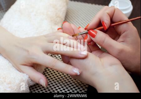 Meister der Maniküre stellt Nagelverlängerungsgel im Schönheitssalon her. Professionelle Pflege der Hände. Stockfoto