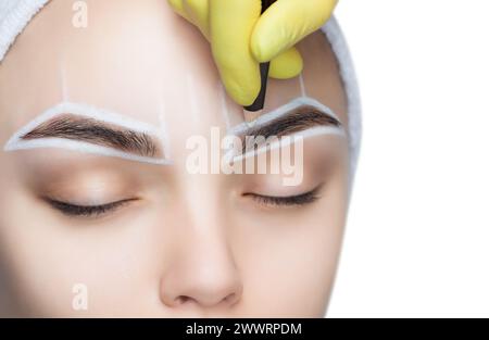 Permanent Make-up für Augenbrauen einer schönen Frau mit dicken Augenbrauen im Schönheitssalon. Nahaufnahme-Kosmetikerin, die Augenbrauen tätowiert. Stockfoto