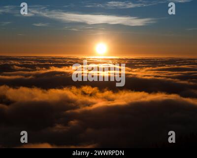 Sonnenuntergang über Wolken mit winterlicher Bergumkehr Stockfoto