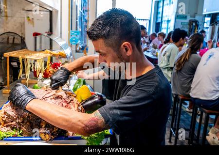 Ein Mann, der Rindfleisch in Einem Café auf dem San Telmo Indoor Market (Mercado de San Telmo), Buenos Aires, Argentinien schnitzt. Stockfoto