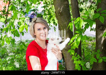 Ein weißes Mädchen, das im Park spaziert, die Katzen am Gurtzeug Stockfoto