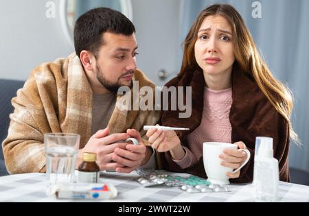 Frau und Mann in Plaids gehüllt mit Symptomen von Kälte zu Hause Stockfoto