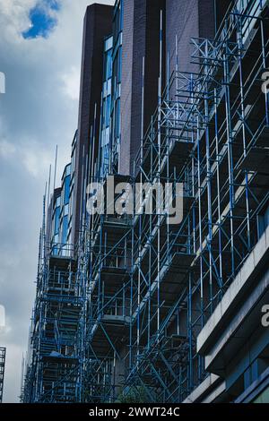 Städtische Baustelle mit kompliziertem Gerüst vor einem modernen Gebäude unter bewölktem Himmel in Leeds, Großbritannien. Stockfoto