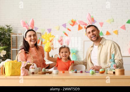 Kleines Mädchen in Hasenohren, das von ihren Eltern zu Hause Ostergeschenk bekommt Stockfoto