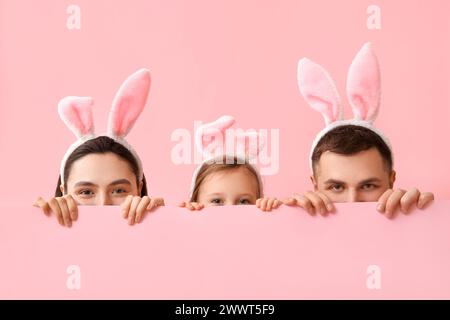 Glückliche Familie in Osterhasenohren versteckt sich auf rosa Hintergrund Stockfoto