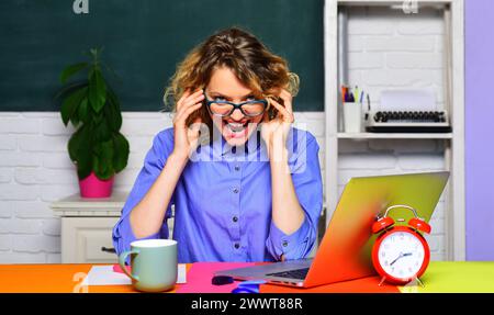 Lustige Lehrerin oder Schülerin in Brille im Klassenzimmer. Lehrerin hält Vorlesung an der Universität. Bildung und Wissen. Lächelnder Lehrer sitzt Stockfoto