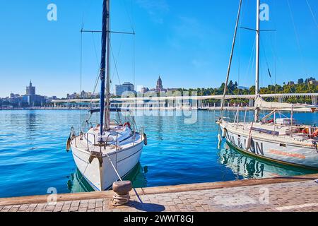 Der Blick auf das moderne weiße Baldachin von Palm Grove of Surprises Promenade, gesehen durch die Yachten hinter dem Hafen von Malaga, Spanien Stockfoto