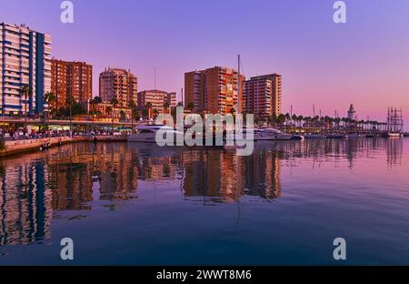 Das Ufer des Hafens von Malaga mit Häusern, Cafés und Yachten am Muelle UNO Pier, der sich auf dem Wasser des Meeres spiegelt, Spanien Stockfoto