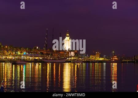 Der Abend im Hafen von Malaga mit dem Leuchtturm La Farola, Yachten, Touristencafés und Geschäften an Muelle UNO, Costa Del Sol, Spanien Stockfoto