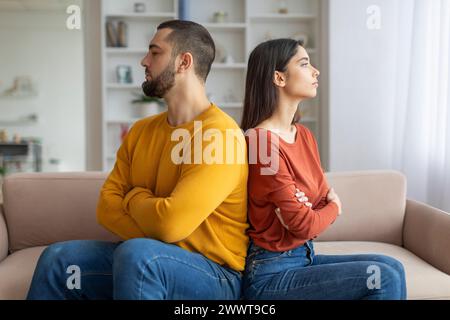 Ein Paar sitzt hinten an hinten und sieht aufgeregt aus Stockfoto