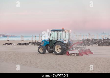 Der Traktor glättet den Sand am öffentlichen Strand am Meer Stockfoto