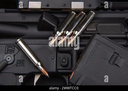 Nahaufnahme von .223 Karabinkartuschen. Geladener Waffenclip. Waffen im Hintergrund. Stockfoto